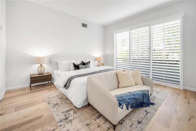 bedroom with visible vents, baseboards, multiple windows, and wood finished floors