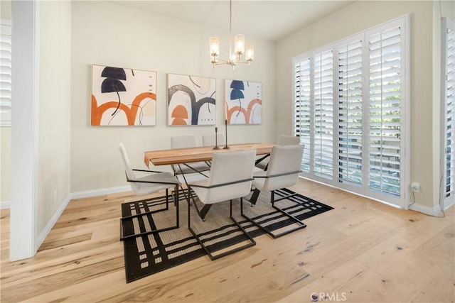 dining area featuring an inviting chandelier, wood finished floors, and baseboards