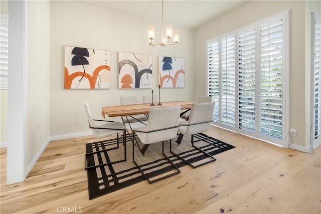 dining room featuring a chandelier, baseboards, and wood finished floors