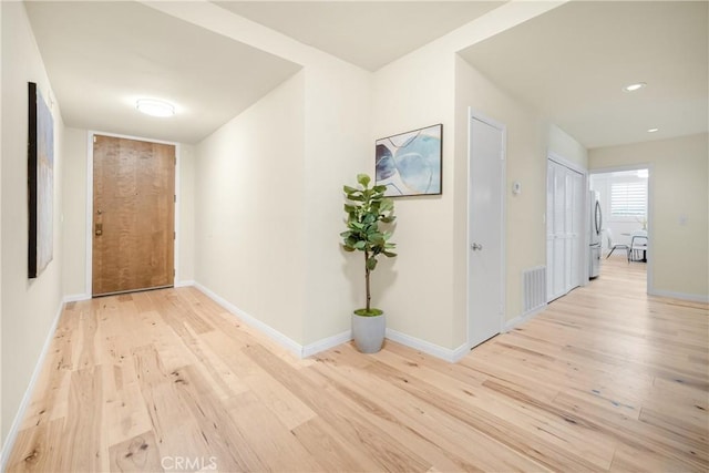 corridor featuring visible vents, light wood-type flooring, and baseboards