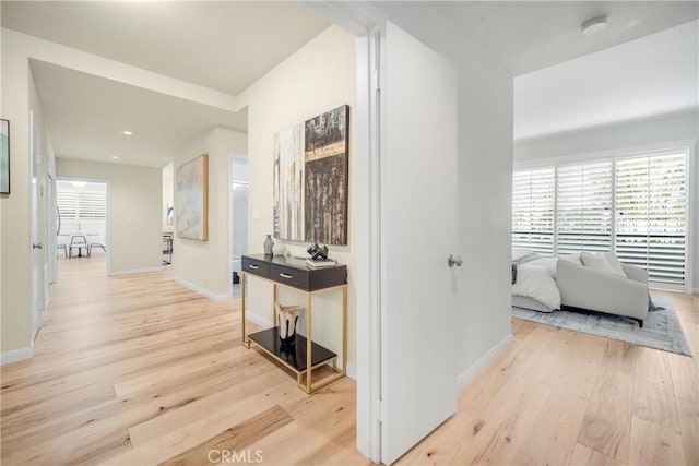 hall with baseboards and light wood-style floors