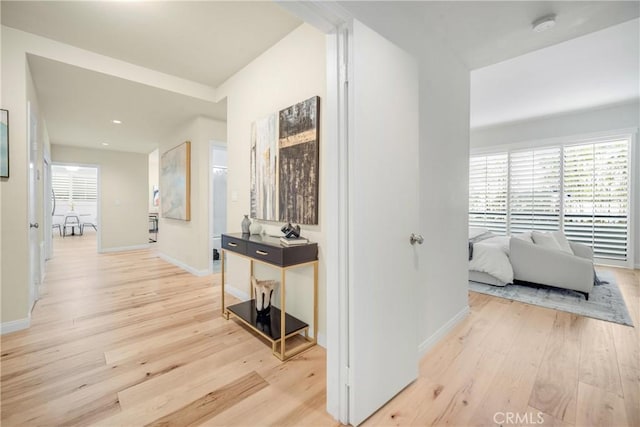 hallway with light wood-type flooring, baseboards, and recessed lighting