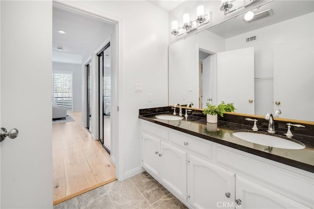 full bathroom with ensuite bath, double vanity, visible vents, and a sink