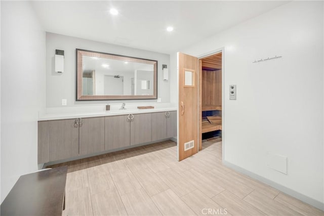 ensuite bathroom with vanity, ensuite bath, recessed lighting, and baseboards