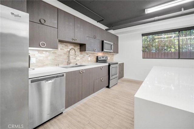 kitchen featuring appliances with stainless steel finishes, light countertops, backsplash, light floors, and a sink