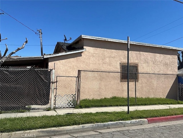 view of home's exterior featuring a gate, stucco siding, and fence