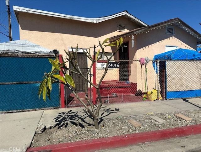 view of front of home featuring stucco siding, a fenced front yard, and a gate