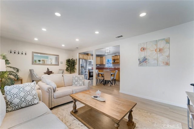 living room with recessed lighting, light wood-style floors, visible vents, and baseboards