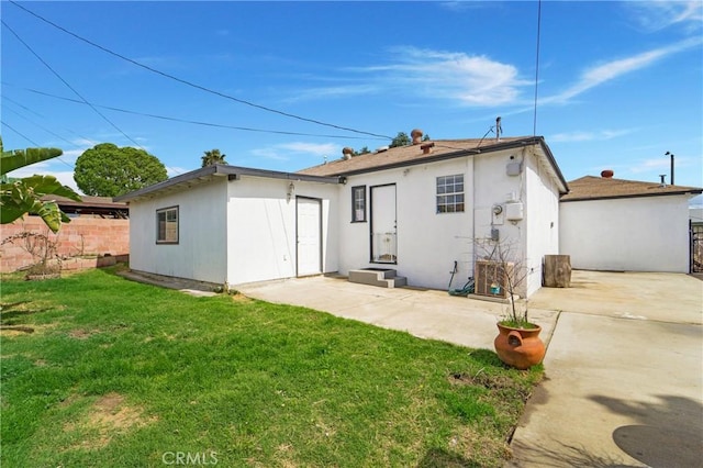 back of house with stucco siding, entry steps, fence, a yard, and a patio area