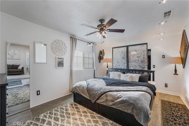 bedroom with visible vents, a ceiling fan, and wood finished floors