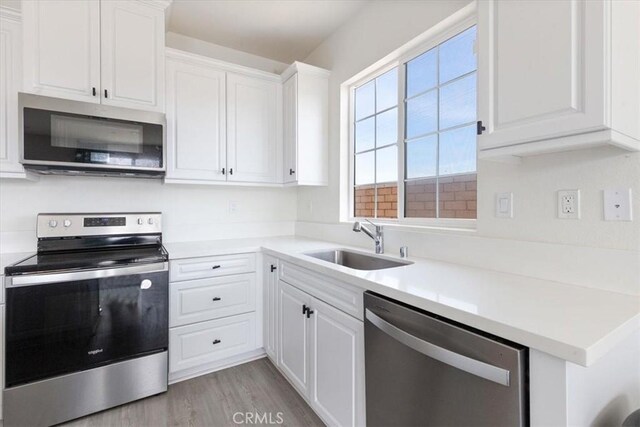 30981 Alister Ln, Winchester, CA 92596 - kitchen with white cabinets, stainless steel appliances, a sink, light wood-type flooring, and light countertops