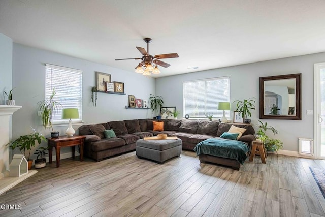 living room with visible vents, baseboards, a fireplace, wood finished floors, and a ceiling fan