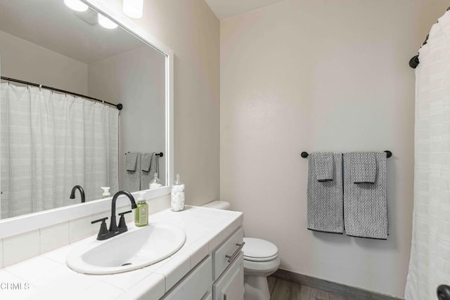 bathroom with baseboards, toilet, wood finished floors, and vanity