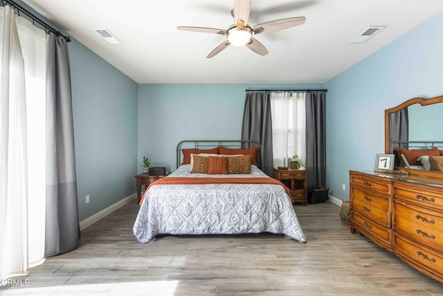 bedroom featuring baseboards, visible vents, light wood finished floors, and ceiling fan