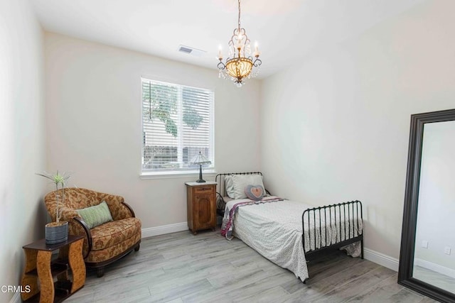 bedroom featuring a notable chandelier, light wood-style flooring, visible vents, and baseboards