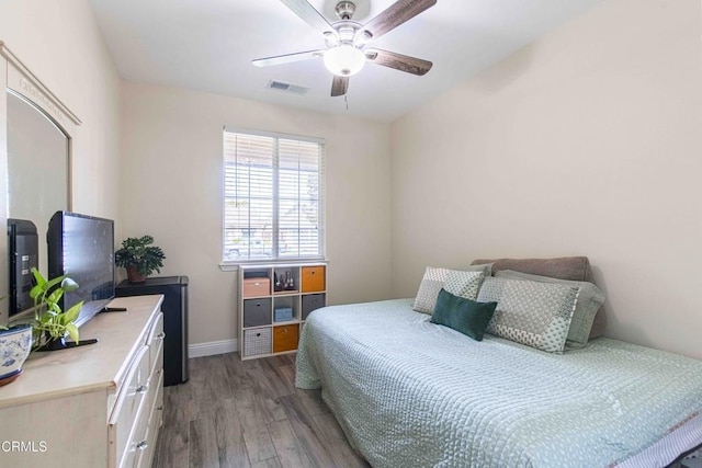 bedroom with ceiling fan, visible vents, baseboards, and wood finished floors