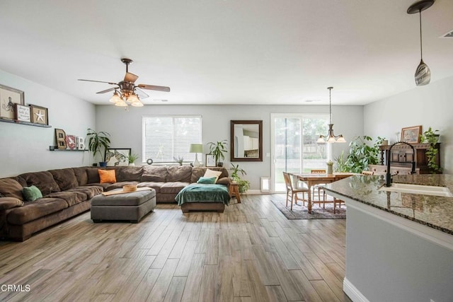 living room featuring ceiling fan, wood finished floors, baseboards, and a healthy amount of sunlight