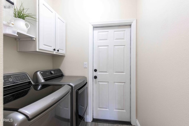 clothes washing area featuring baseboards, cabinet space, and separate washer and dryer