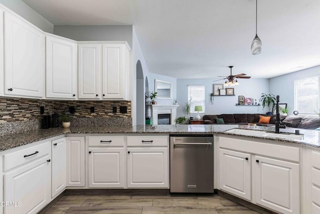 kitchen with open floor plan, backsplash, white cabinets, and a sink