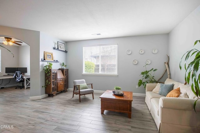 living room with light wood-style flooring, baseboards, visible vents, and ceiling fan