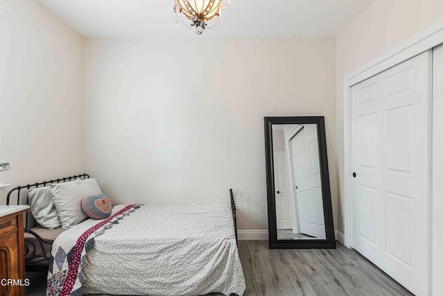 bedroom featuring a notable chandelier, baseboards, and light wood-style floors