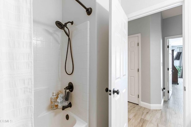 full bathroom with wood finished floors, tub / shower combination, and baseboards