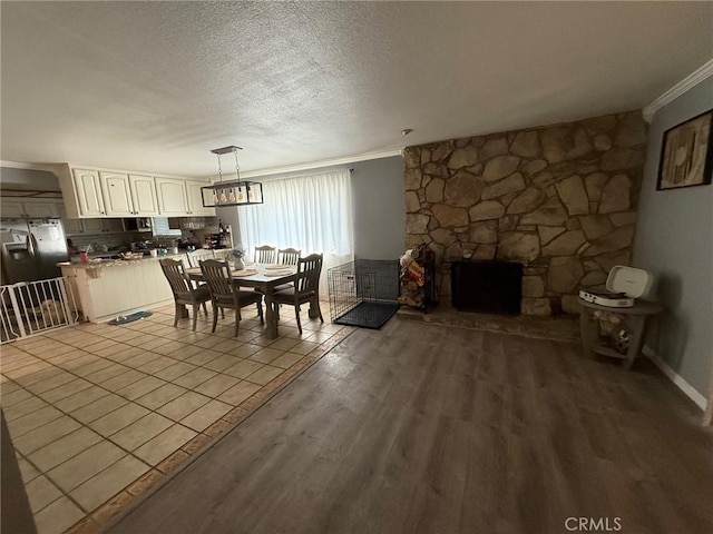 unfurnished dining area with a fireplace, crown molding, wood finished floors, and a textured ceiling