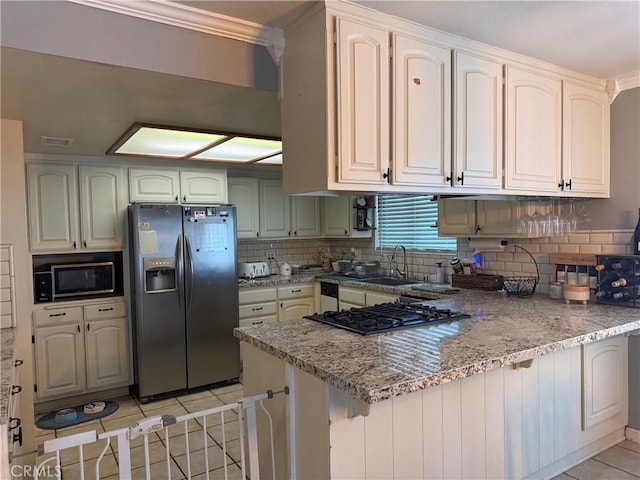 kitchen featuring light tile patterned floors, decorative backsplash, a peninsula, stainless steel appliances, and a sink