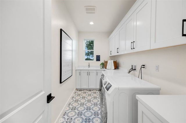 washroom featuring visible vents, a sink, cabinet space, baseboards, and washing machine and clothes dryer