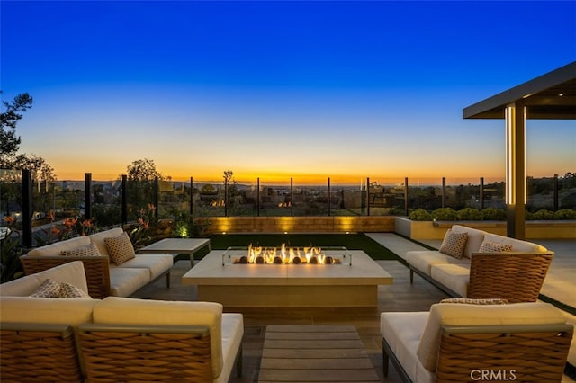 patio terrace at dusk with an outdoor living space with a fire pit and fence