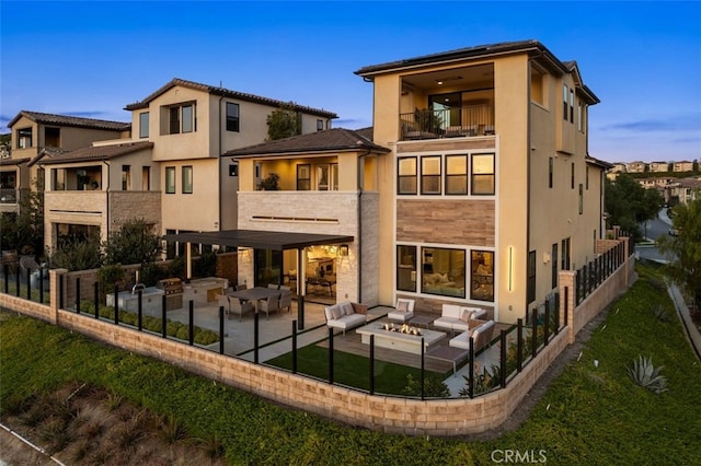 rear view of house featuring fence, an outdoor fire pit, stucco siding, a balcony, and a patio area