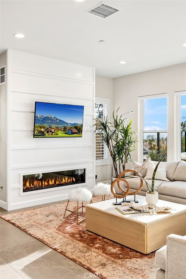 living room with a glass covered fireplace, recessed lighting, and visible vents