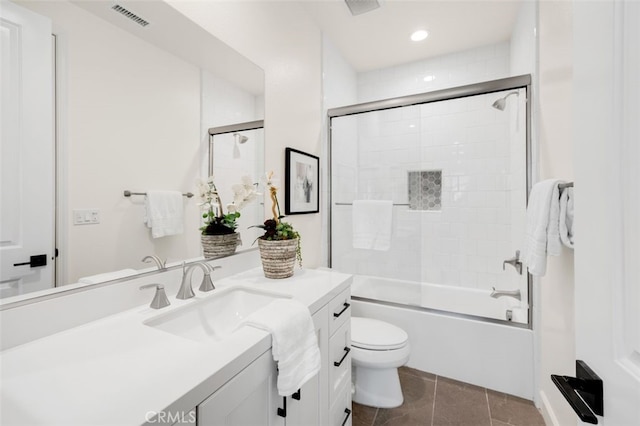 bathroom featuring tile patterned flooring, visible vents, toilet, combined bath / shower with glass door, and vanity