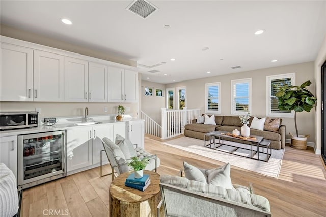 interior space with wine cooler, recessed lighting, visible vents, and light wood finished floors