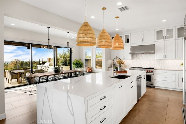 kitchen with visible vents, backsplash, range hood, appliances with stainless steel finishes, and a sink