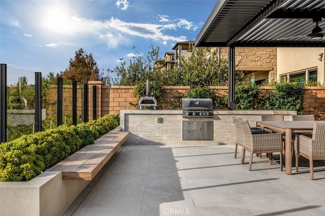 view of patio featuring outdoor dining space, an outdoor kitchen, a grill, and fence