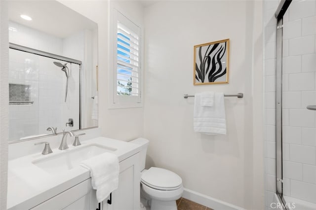 full bathroom featuring baseboards, tiled shower, toilet, and vanity