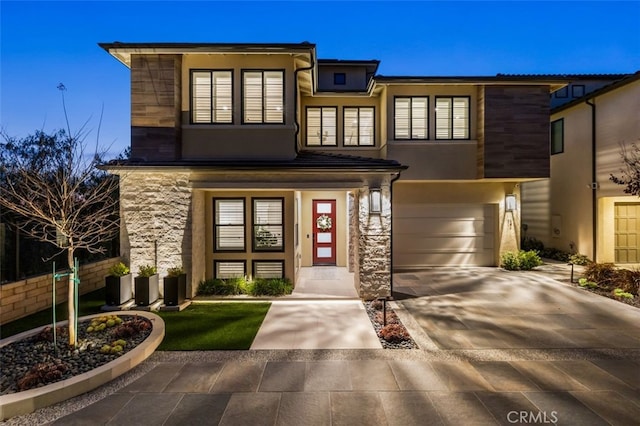 view of front of property with stucco siding, stone siding, a garage, and concrete driveway