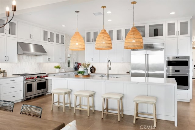 kitchen with ventilation hood, a sink, light countertops, white cabinetry, and premium appliances