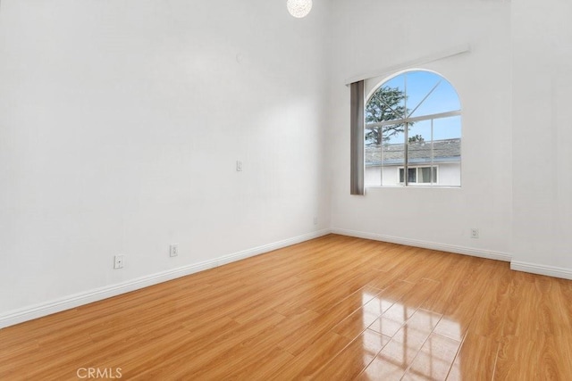 spare room with baseboards and light wood finished floors