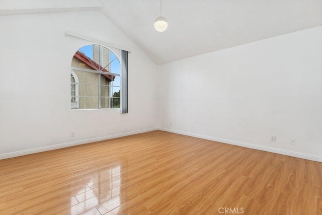 unfurnished room featuring lofted ceiling, light wood-style floors, and baseboards