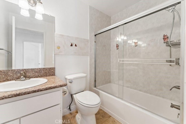 bathroom featuring combined bath / shower with glass door, toilet, and vanity