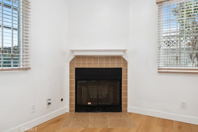 room details featuring baseboards, wood finished floors, and a tile fireplace