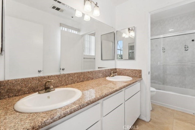 bathroom with double vanity, visible vents, toilet, and a sink