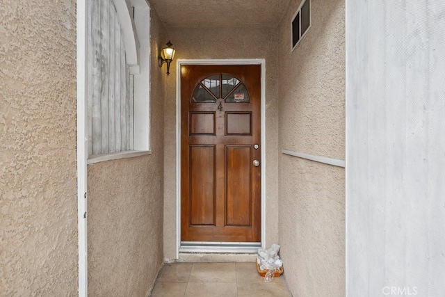 entrance to property with visible vents and stucco siding