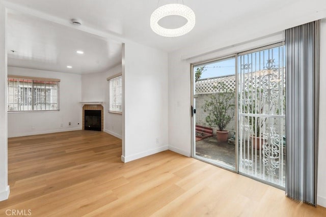 unfurnished living room with recessed lighting, baseboards, wood finished floors, and a tile fireplace