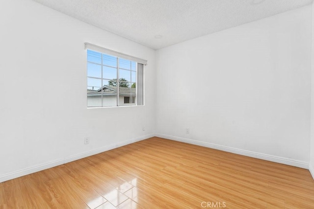 unfurnished room featuring baseboards, a textured ceiling, and light wood-style floors