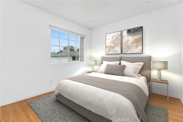 bedroom with baseboards, a textured ceiling, and wood finished floors