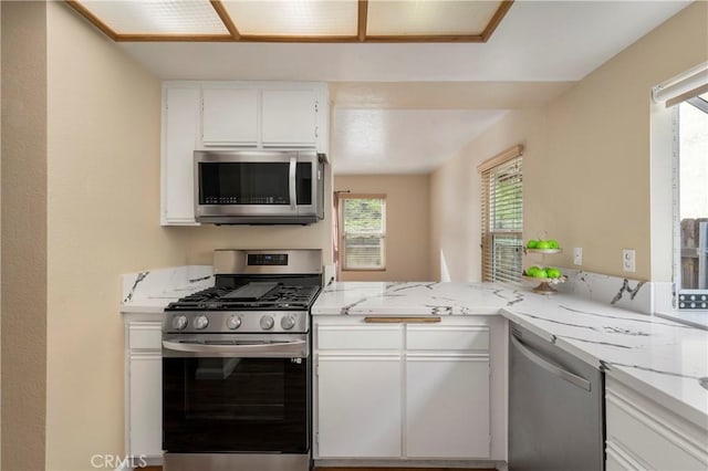 kitchen featuring light stone counters, appliances with stainless steel finishes, and white cabinetry