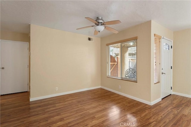 empty room with visible vents, baseboards, ceiling fan, wood finished floors, and a textured ceiling